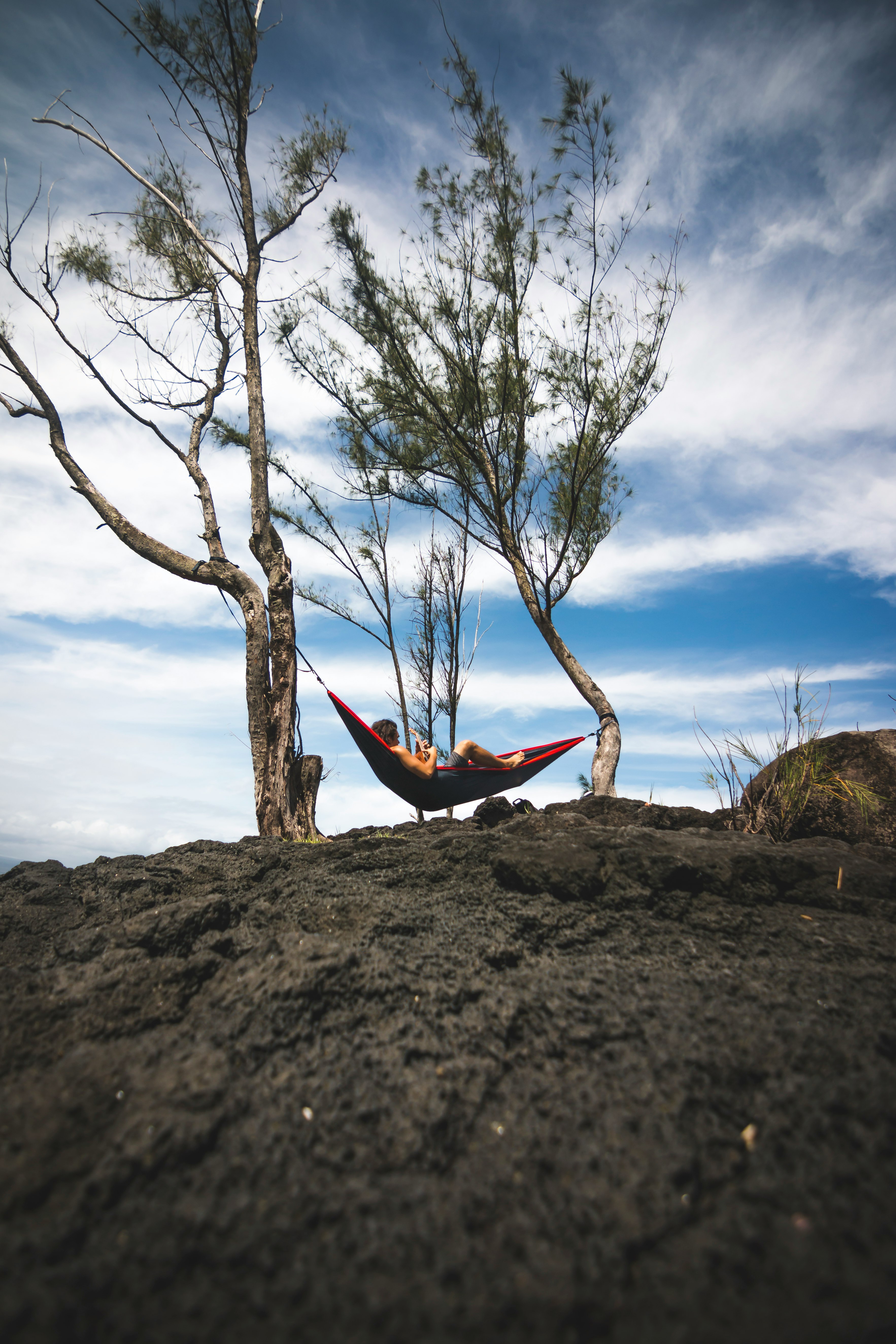 person lying on black and red hammock during daytime